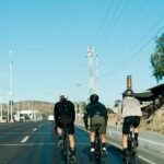 three bicyclists riding down the road on a sunny day